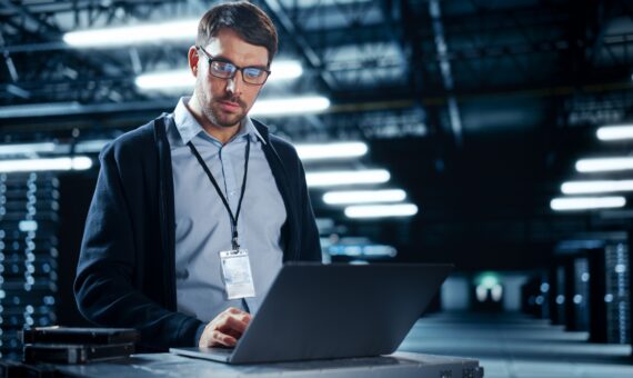 IT Specialist looking at laptop in data center.